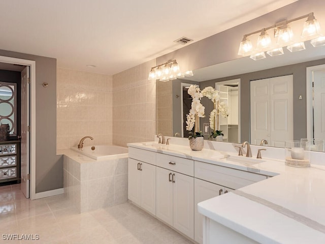 bathroom featuring vanity, tiled tub, and tile patterned flooring