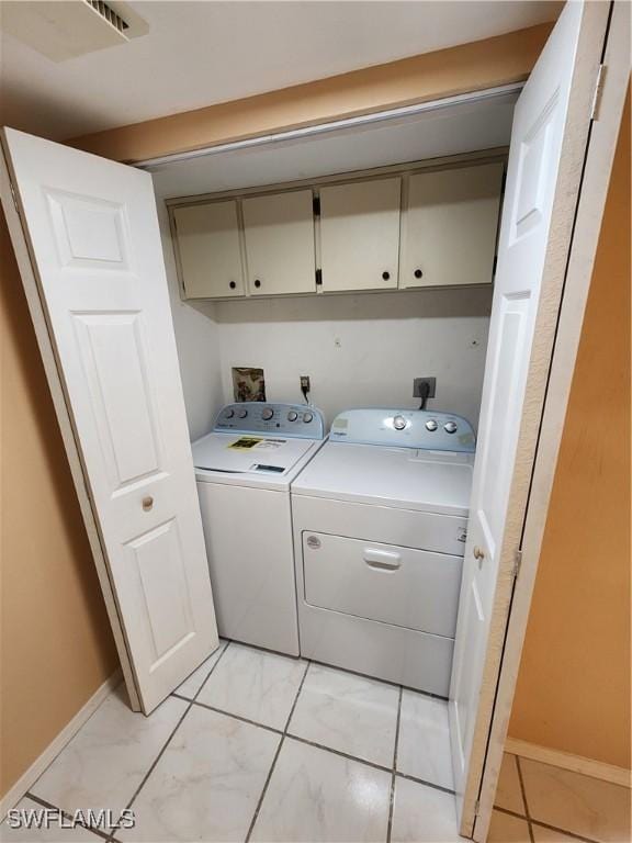 washroom with light tile patterned flooring, cabinets, and washer and dryer