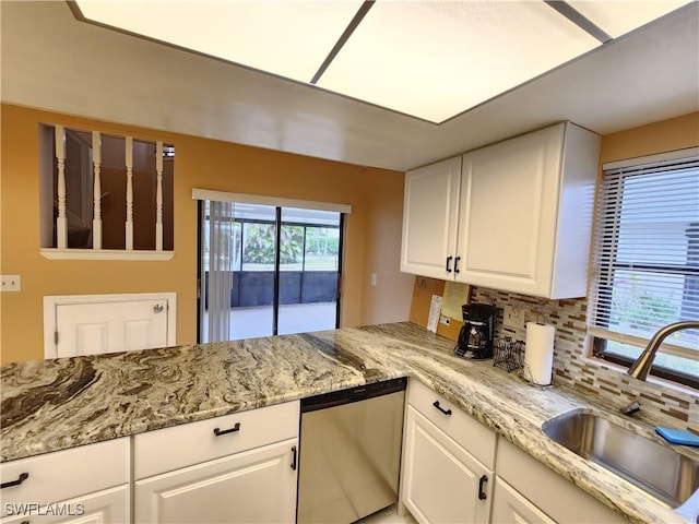 kitchen featuring light stone countertops, white cabinetry, sink, backsplash, and stainless steel dishwasher