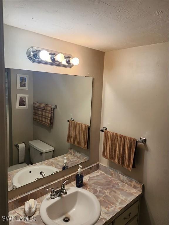 bathroom with vanity, toilet, and a textured ceiling