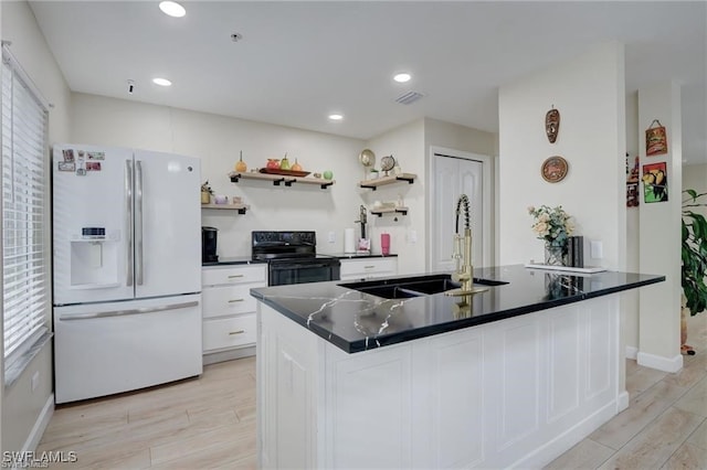 kitchen featuring white refrigerator with ice dispenser, sink, plenty of natural light, white cabinetry, and black range with electric cooktop