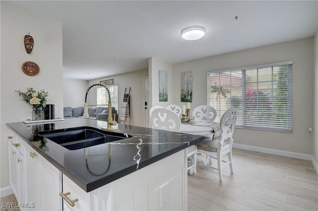 kitchen featuring white cabinets, light wood-type flooring, and sink