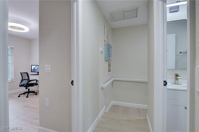 corridor with sink and light hardwood / wood-style flooring