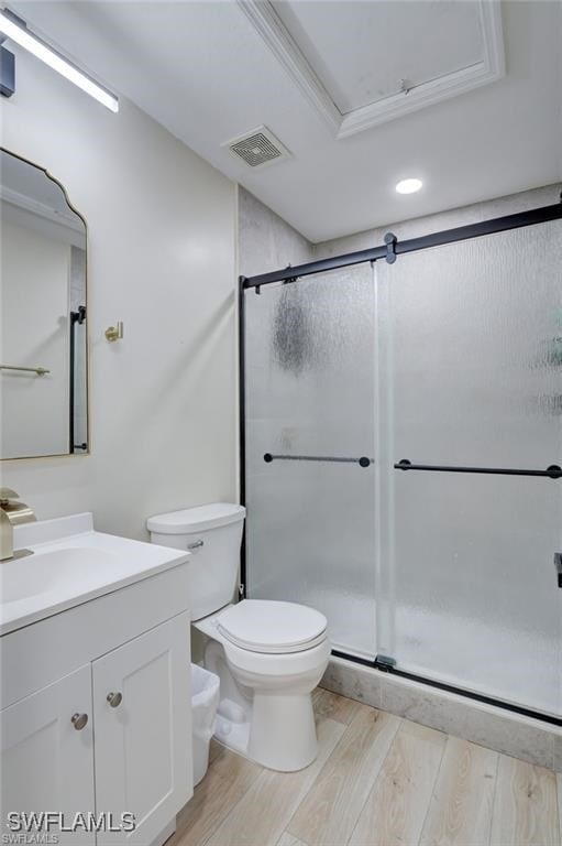 bathroom with wood-type flooring, vanity, toilet, walk in shower, and crown molding