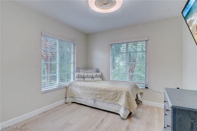 bedroom with light hardwood / wood-style floors and multiple windows