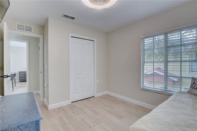 bedroom featuring multiple windows, a closet, and light wood-type flooring