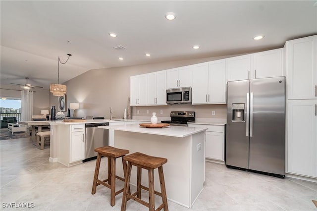 kitchen with lofted ceiling, appliances with stainless steel finishes, and a kitchen island