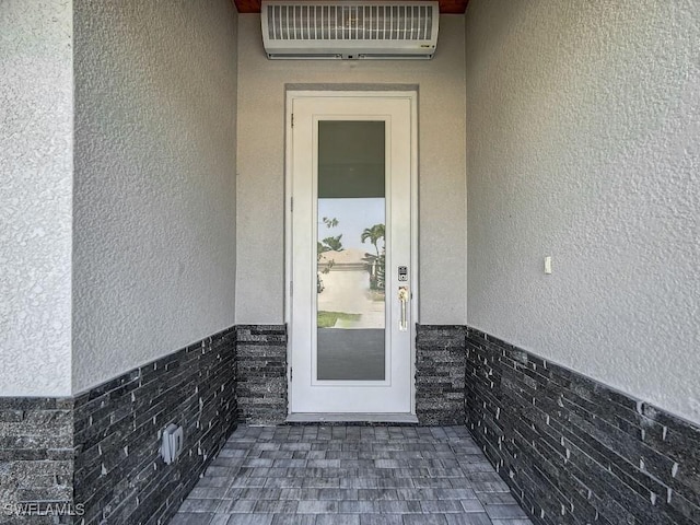 view of exterior entry with a wall mounted air conditioner