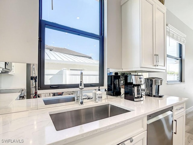 kitchen with light stone counters, stainless steel dishwasher, and white cabinets