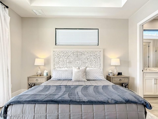 bedroom with connected bathroom and light hardwood / wood-style flooring