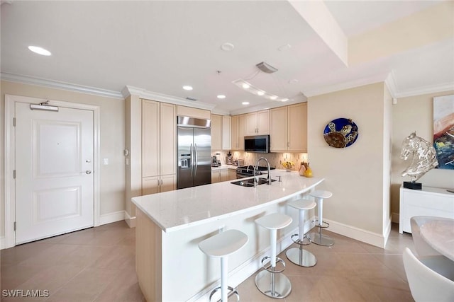 kitchen featuring appliances with stainless steel finishes, sink, a breakfast bar area, light tile patterned floors, and light stone counters