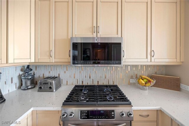 kitchen featuring stainless steel appliances, tasteful backsplash, and light stone counters