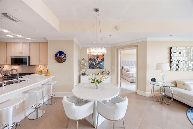 tiled dining space with crown molding, an inviting chandelier, a raised ceiling, and sink