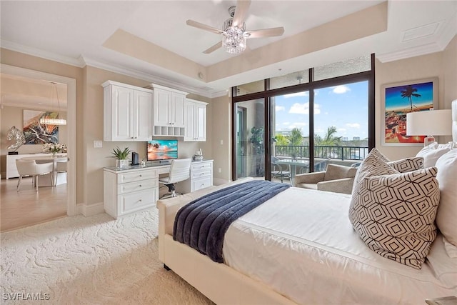 carpeted bedroom with a tray ceiling, ceiling fan, built in desk, crown molding, and access to exterior