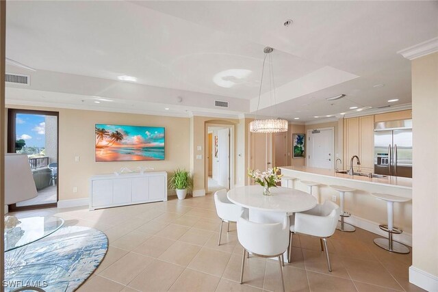 dining space featuring a tray ceiling, sink, crown molding, and light tile patterned flooring