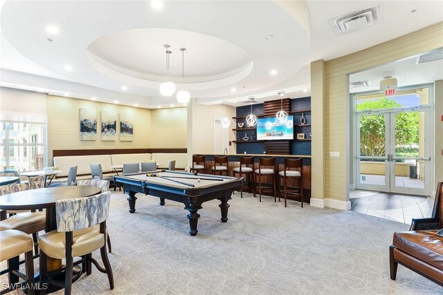 rec room featuring french doors, pool table, indoor bar, a raised ceiling, and light colored carpet