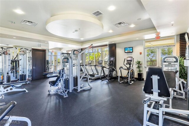 exercise room with french doors and a raised ceiling