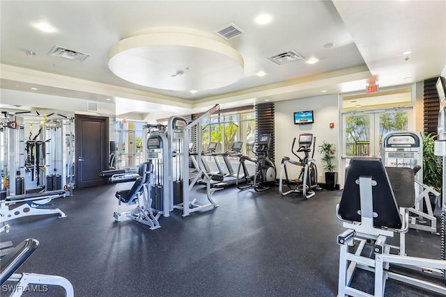 exercise room with a raised ceiling and french doors