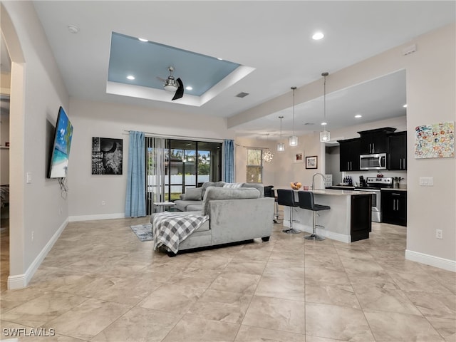 living room with sink and a tray ceiling