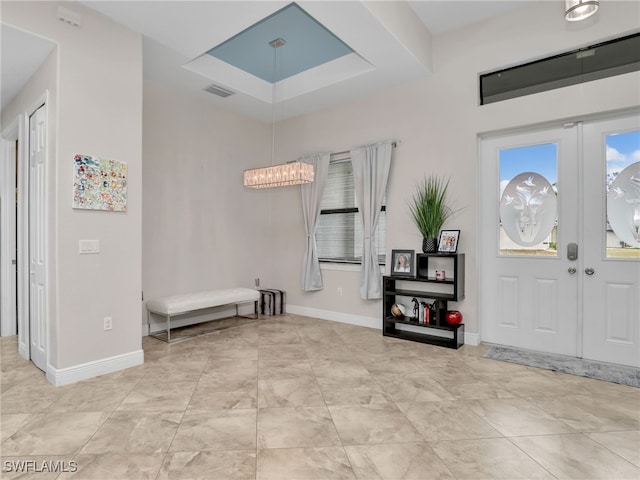 foyer entrance with french doors and a raised ceiling