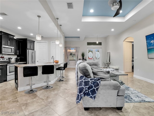 living room with sink, ceiling fan, and a raised ceiling