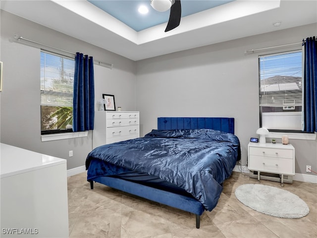 bedroom with ceiling fan and a raised ceiling