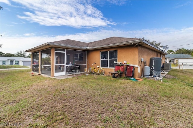 rear view of property featuring a lawn, central AC, and a sunroom