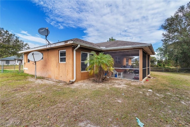 rear view of house featuring a lawn and a sunroom