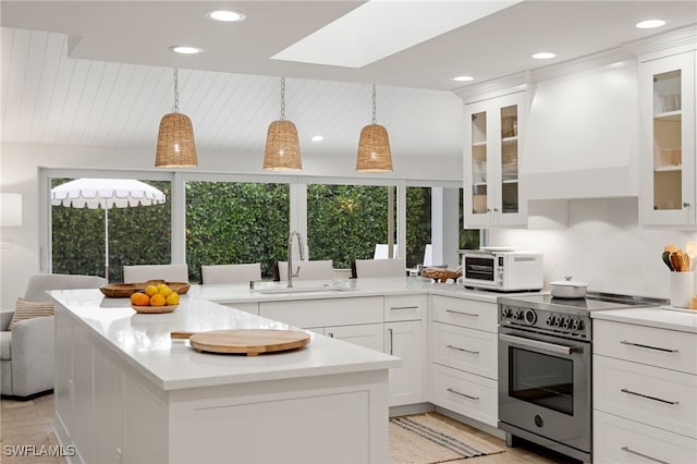 kitchen featuring high end stove, custom range hood, a peninsula, and a sink