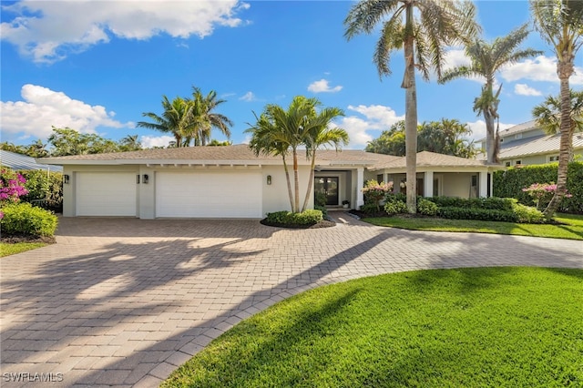 ranch-style home with stucco siding, decorative driveway, a front lawn, and an attached garage