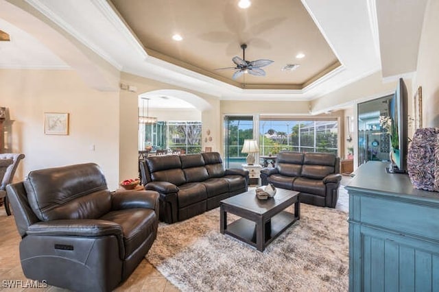 tiled living room featuring ceiling fan, a raised ceiling, and ornamental molding