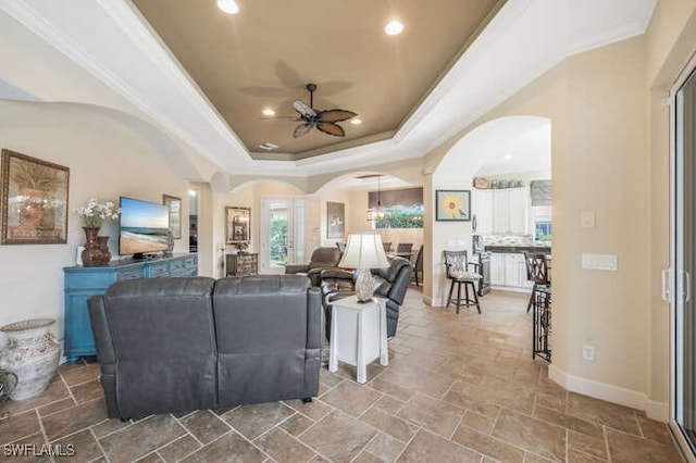 living room with ceiling fan, crown molding, and a raised ceiling