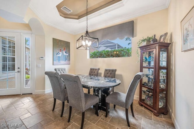 dining room featuring a chandelier, a raised ceiling, and crown molding