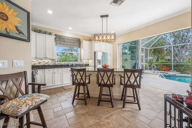 kitchen with decorative light fixtures, decorative backsplash, white cabinets, and stainless steel fridge with ice dispenser