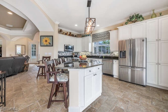 kitchen with decorative light fixtures, white cabinetry, appliances with stainless steel finishes, and a kitchen island