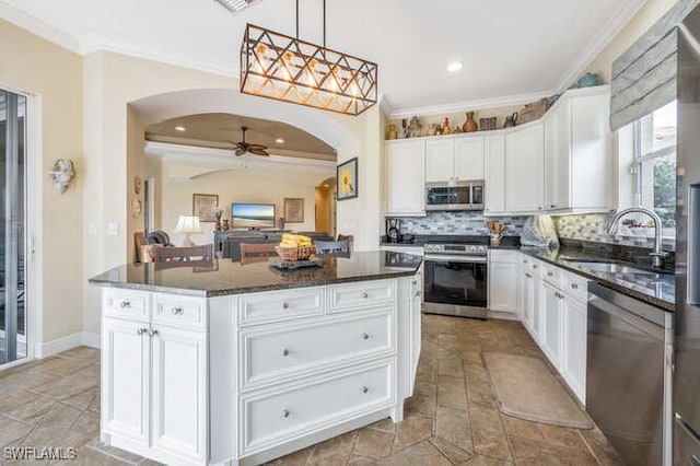 kitchen featuring appliances with stainless steel finishes, sink, decorative light fixtures, white cabinetry, and a center island