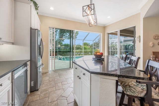 kitchen featuring appliances with stainless steel finishes, decorative light fixtures, white cabinetry, a breakfast bar, and a kitchen island