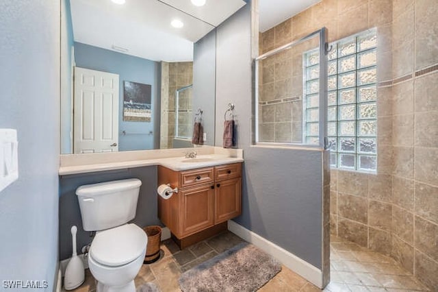 bathroom with tiled shower, vanity, and toilet