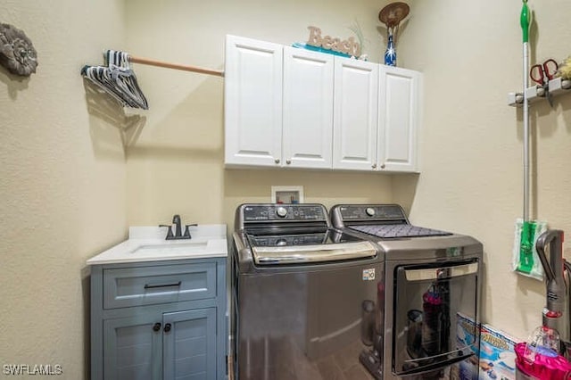 laundry area with sink, washing machine and clothes dryer, and cabinets