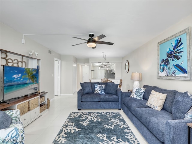 living room with ceiling fan with notable chandelier and light tile patterned floors