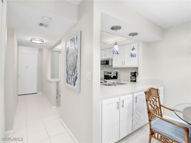 bar with sink, appliances with stainless steel finishes, white cabinetry, light tile patterned flooring, and decorative light fixtures