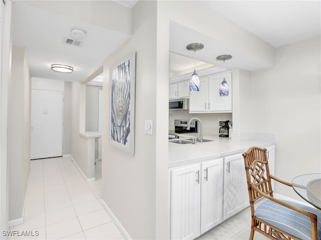 interior space with hanging light fixtures, light tile patterned floors, appliances with stainless steel finishes, and a sink