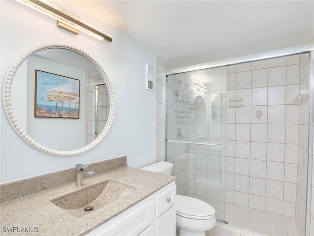 bathroom with vanity, toilet, and a shower with shower door