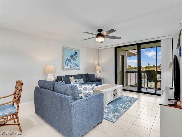 living room with a ceiling fan, expansive windows, light tile patterned flooring, and baseboards