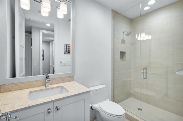 bathroom with vanity, a shower with door, and toilet