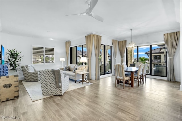 living room featuring ceiling fan with notable chandelier and light wood-type flooring