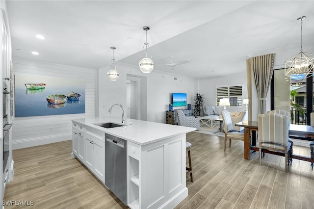 kitchen with decorative light fixtures, dishwasher, white cabinetry, sink, and an island with sink