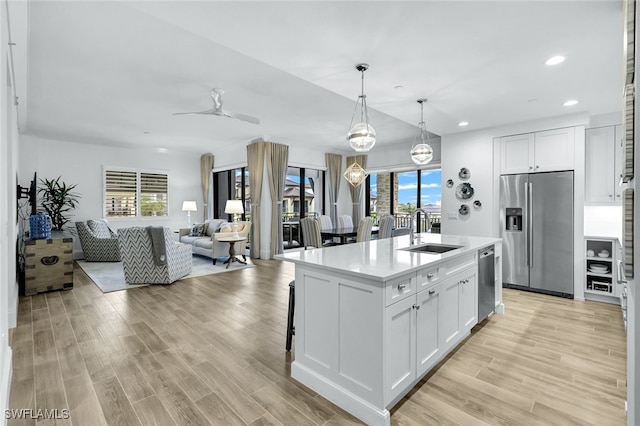 kitchen with stainless steel appliances, a kitchen island with sink, sink, and white cabinets