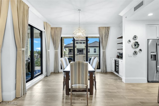 dining room with an inviting chandelier, bar, and beverage cooler