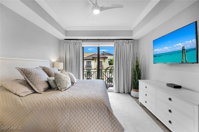 carpeted bedroom featuring access to exterior, a tray ceiling, and ceiling fan